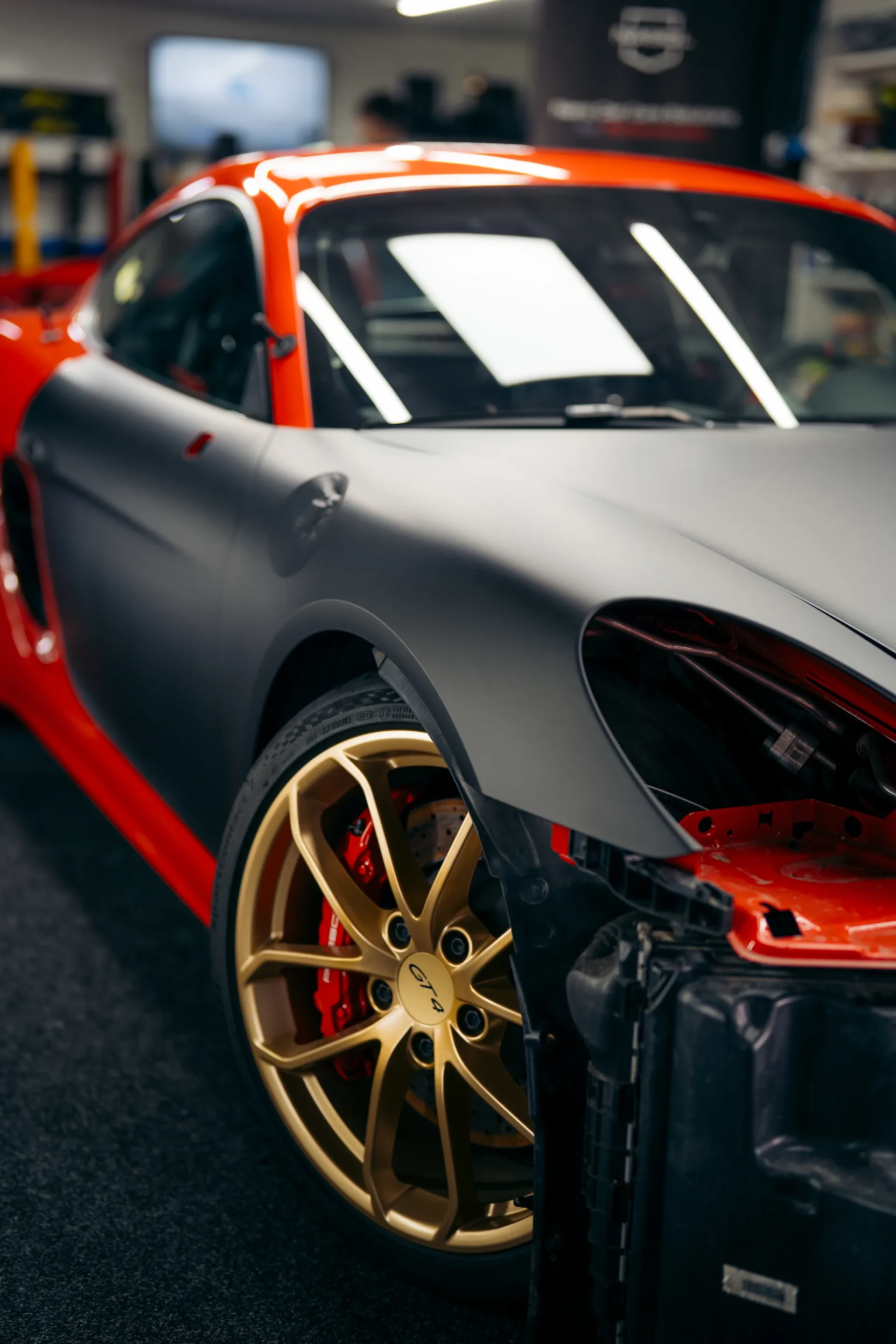 Matte black Porsche with red accents and gold wheels