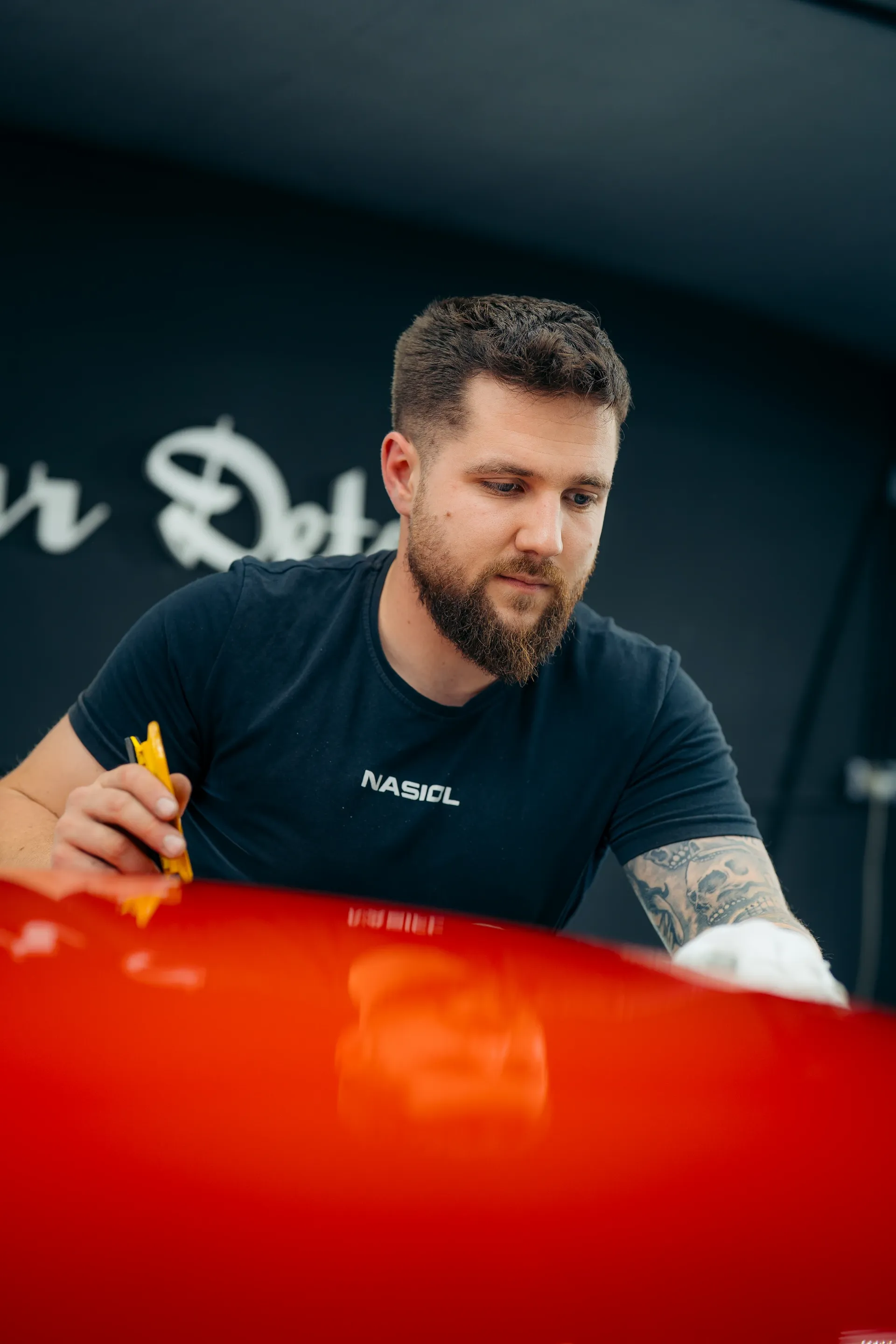 Detailing specialist applying protective film to a red Porsche