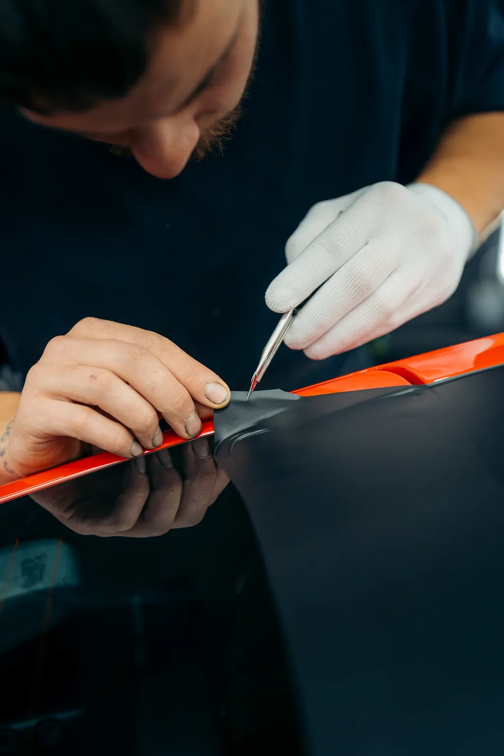 Technician applying red protective film to a BMW M3 CS