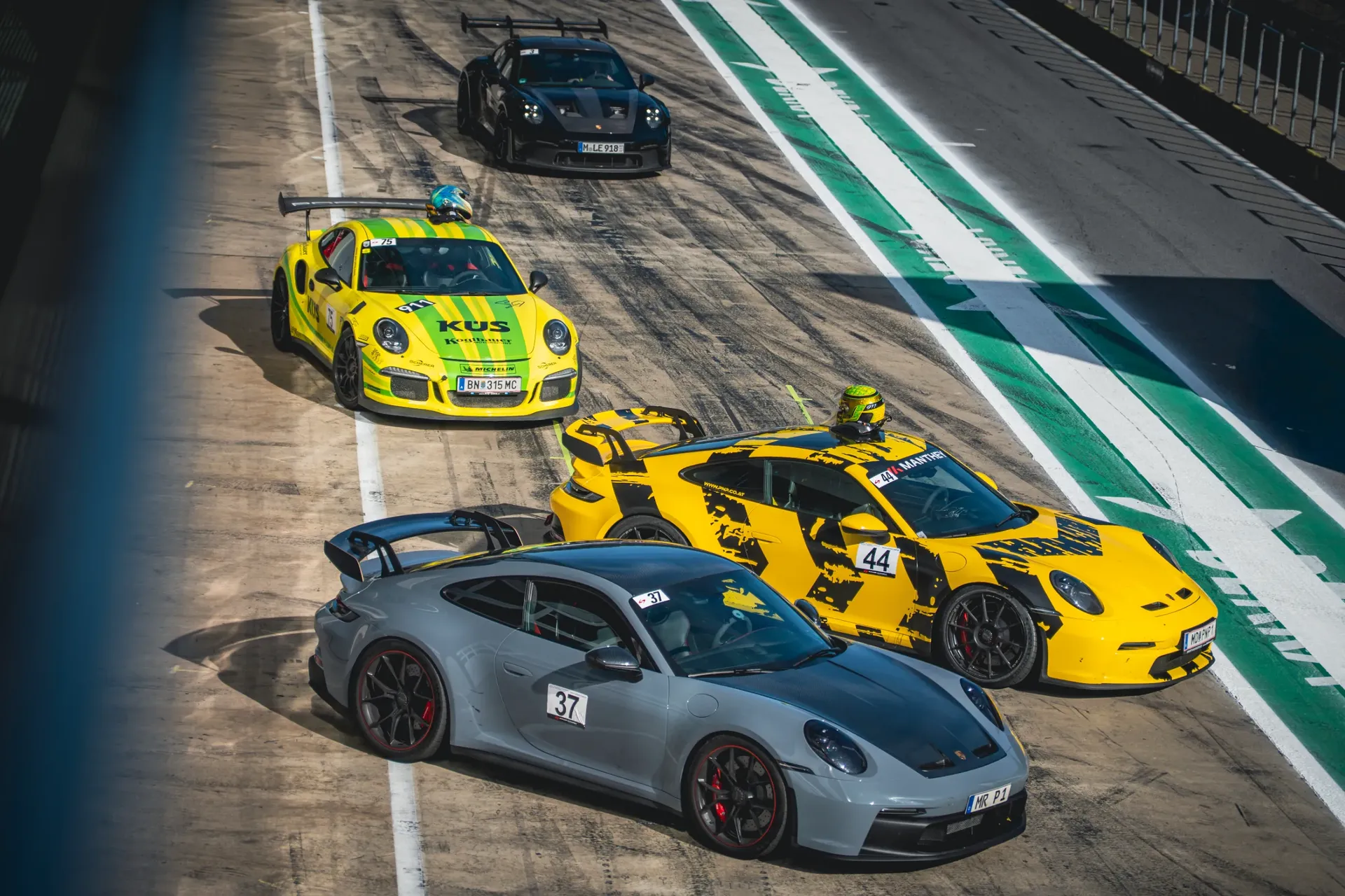 Elevated view of four Porsche sports cars lined up in the pit lane during Porsche Day at the Red Bull Ring.